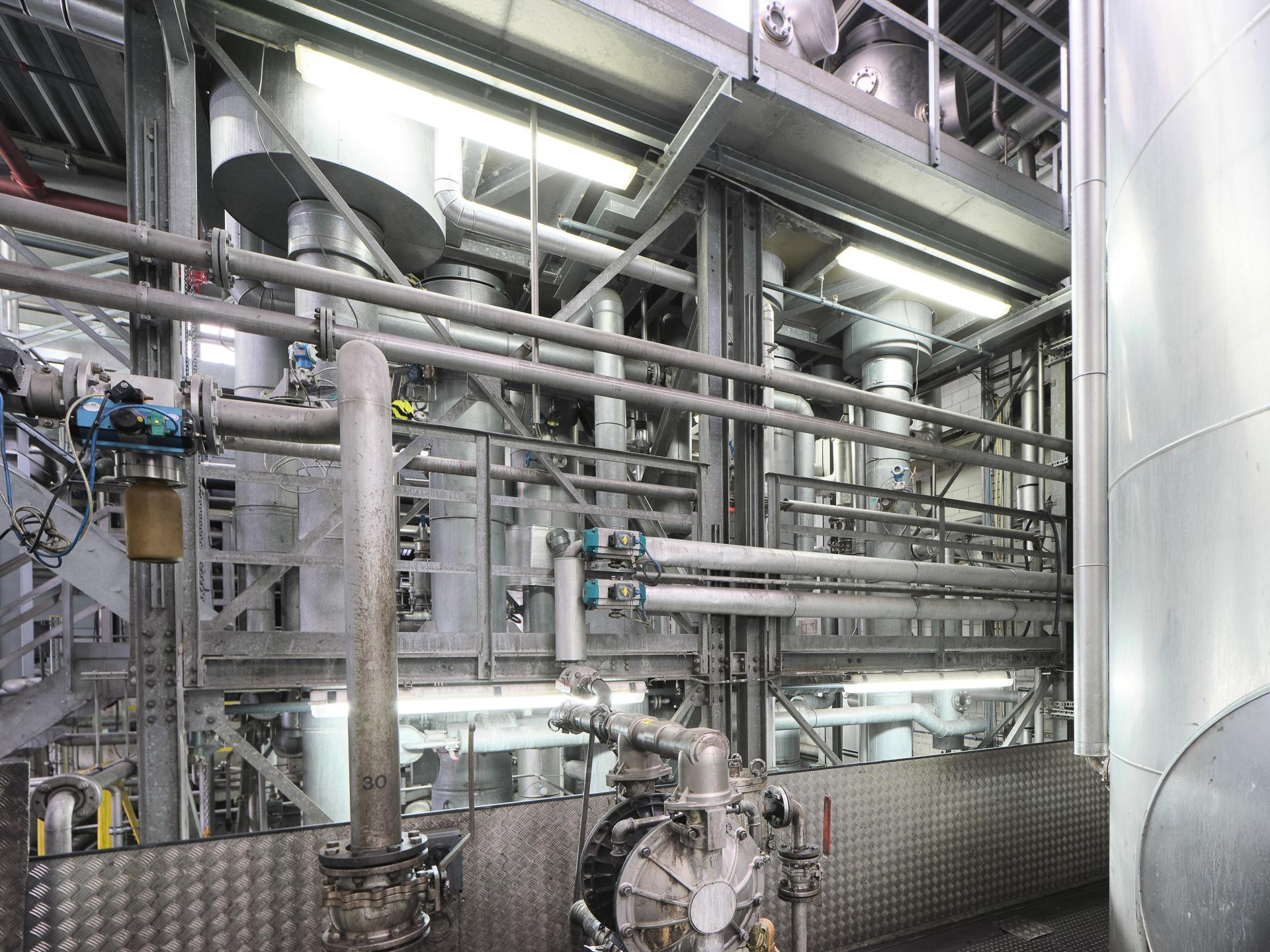 Stahl Armaturen auf mehreren Stockwerken. Man sieht viele stählerne Röhren und Behälter.